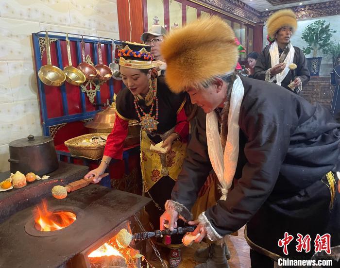 圖為人們在火上烤節日美食“結達”?！∪轿木?攝