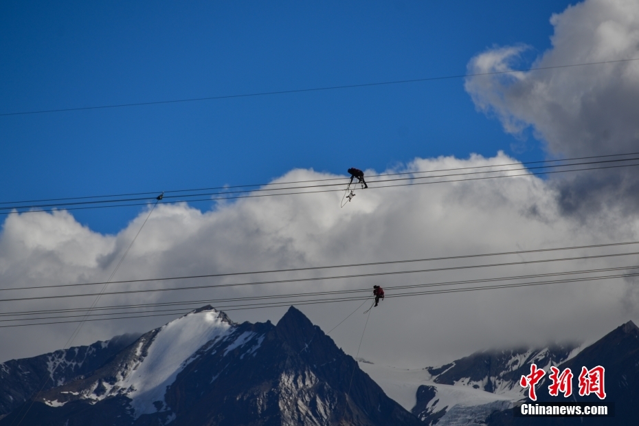 資料圖為2020年6月23日,西藏阿里聯(lián)網(wǎng)工程施工人員在日喀則希夏邦馬雪山附近進行走線作業(yè),安裝絕緣設備。 <a target='_blank' href='/'><p align=